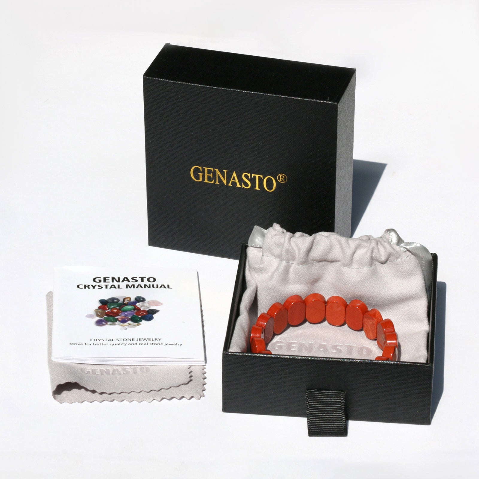 A GENASTO branded black gift box containing a red beaded bracelet, a gray drawstring pouch, a crystal manual booklet, and a gray cleaning cloth displayed on a white surface